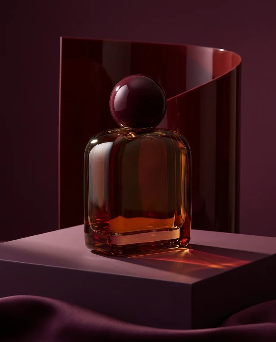 Amber perfume bottle in a sculptural plum-colored campaign scene