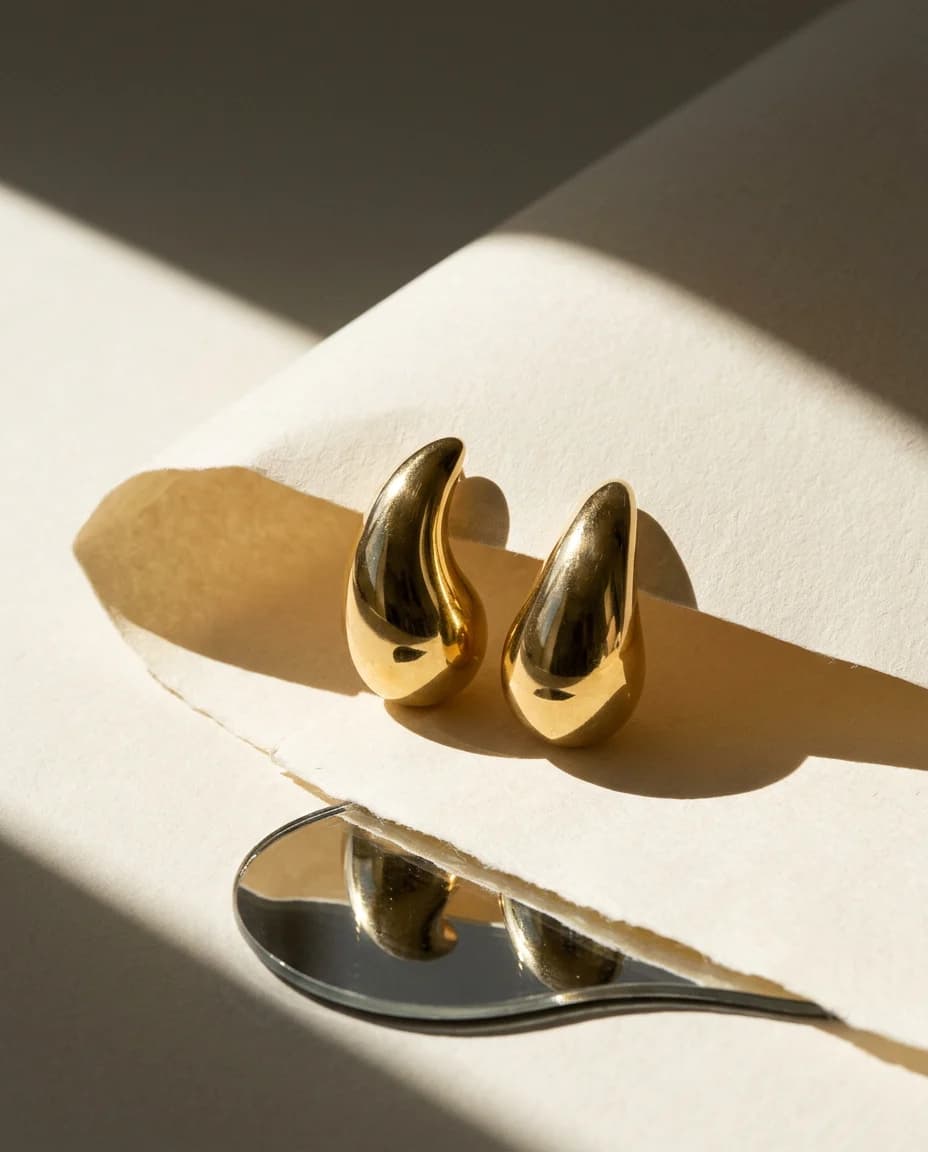 Sculptural gold jewelry in an ivory editorial still life